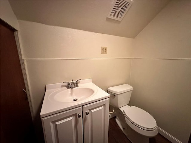 bathroom featuring visible vents, toilet, lofted ceiling, wood finished floors, and vanity