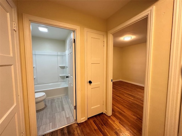 corridor featuring dark wood-style flooring and baseboards