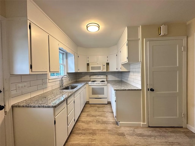 kitchen with light wood finished floors, tasteful backsplash, white cabinetry, a sink, and white appliances