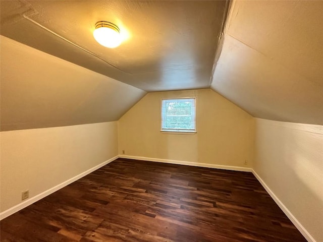 bonus room with dark wood-style floors, vaulted ceiling, and baseboards