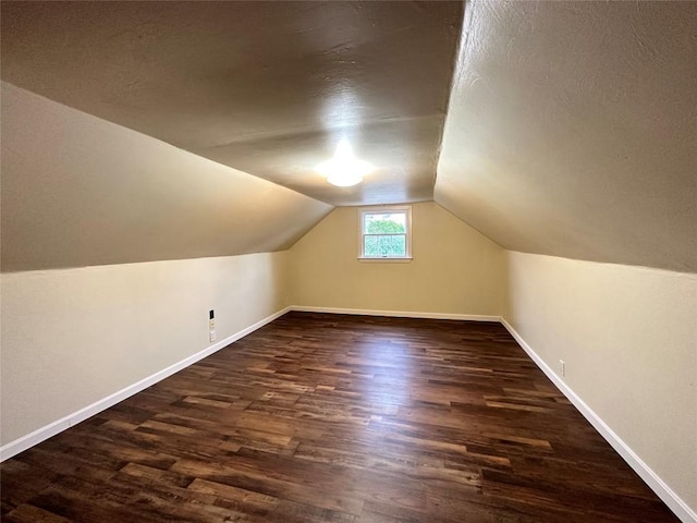 additional living space with vaulted ceiling, dark wood-style flooring, and baseboards