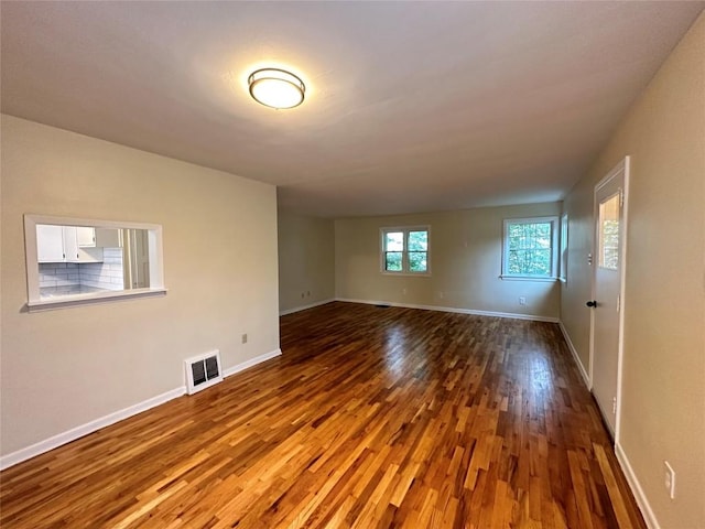 spare room featuring wood finished floors, visible vents, and baseboards