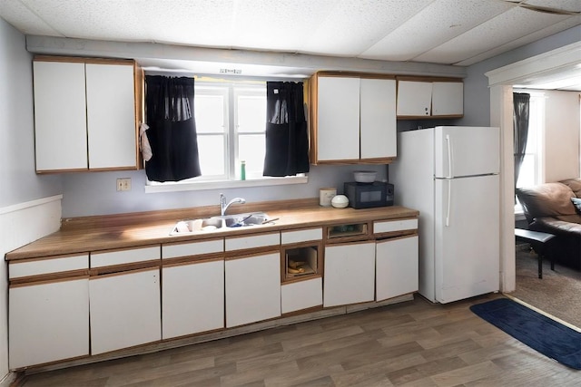 946 W 17th St, Erie, PA 16502 - kitchen featuring freestanding refrigerator, white cabinets, black microwave, and light wood-type flooring