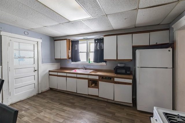 946 W 17th St, Erie, PA 16502 - kitchen featuring freestanding refrigerator, black microwave, a drop ceiling, light wood-type flooring, and white cabinetry
