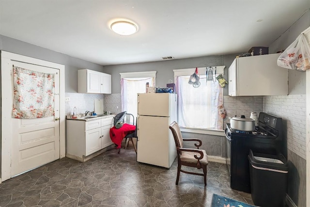 946 W 17th St, Erie, PA 16502 - kitchen with freestanding refrigerator, black range with gas stovetop, white cabinetry, and light countertops