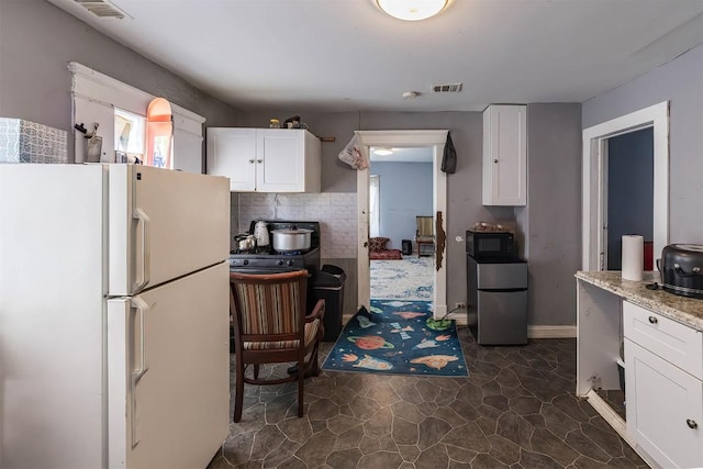 946 W 17th St, Erie, PA 16502 - kitchen with freestanding refrigerator, black microwave, white cabinetry, and decorative backsplash