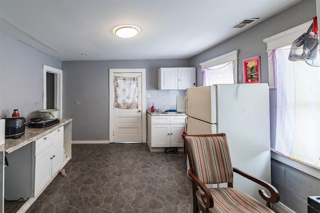 946 W 17th St, Erie, PA 16502 - kitchen featuring freestanding refrigerator, white cabinets, decorative backsplash, and light stone counters