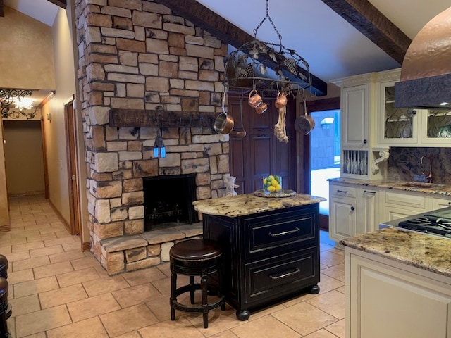 kitchen featuring white cabinets, light stone counters, a kitchen island, and range hood