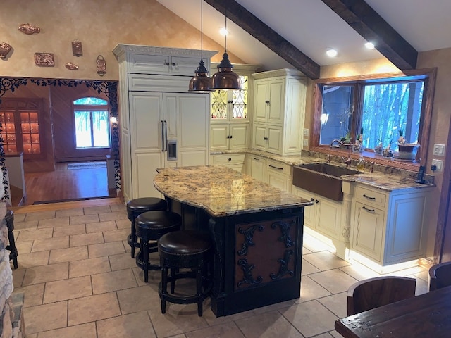 kitchen with a center island, sink, light stone countertops, paneled fridge, and decorative light fixtures