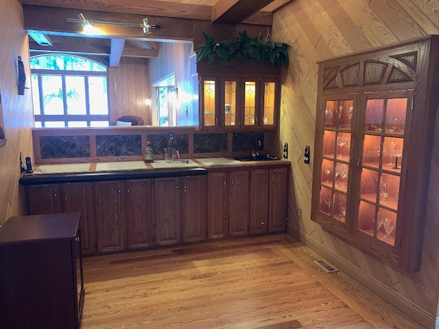 bar with beamed ceiling, light hardwood / wood-style floors, wooden walls, and sink