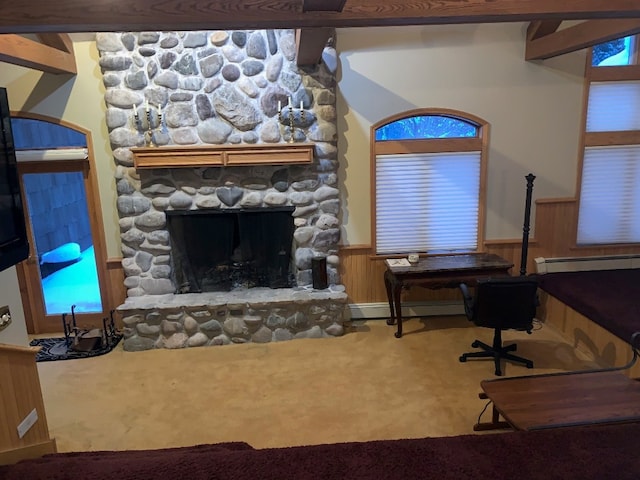 carpeted living room with beamed ceiling, wood walls, a stone fireplace, and a baseboard radiator