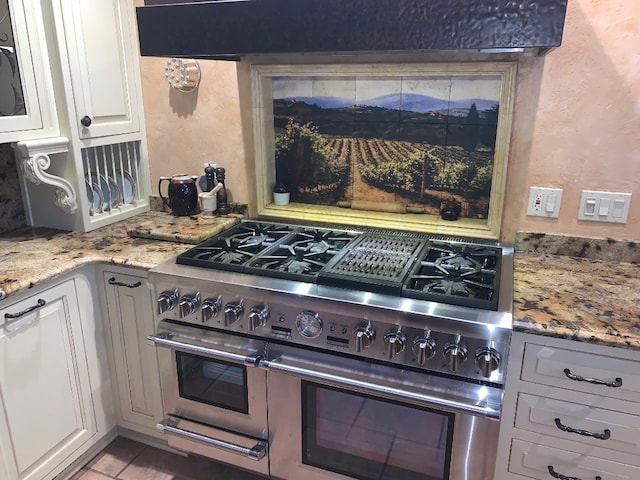 kitchen featuring white cabinetry, light stone countertops, range hood, range with two ovens, and light tile patterned flooring