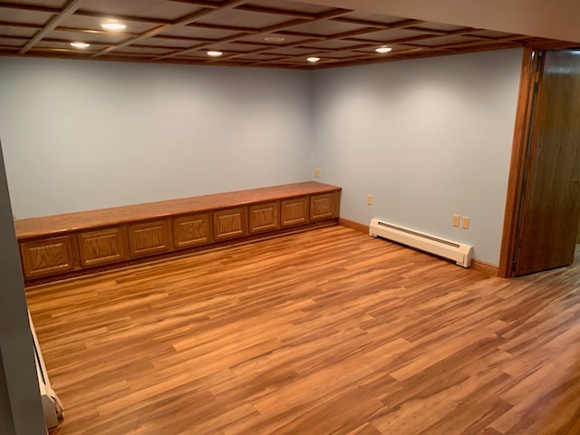 basement with light wood-type flooring and a baseboard radiator