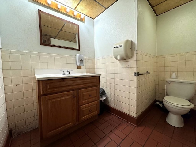 bathroom with vanity, tile walls, and toilet