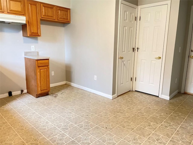 2517 Mccain Ave, Erie, PA 16510 - kitchen with under cabinet range hood, brown cabinets, light countertops, and baseboards