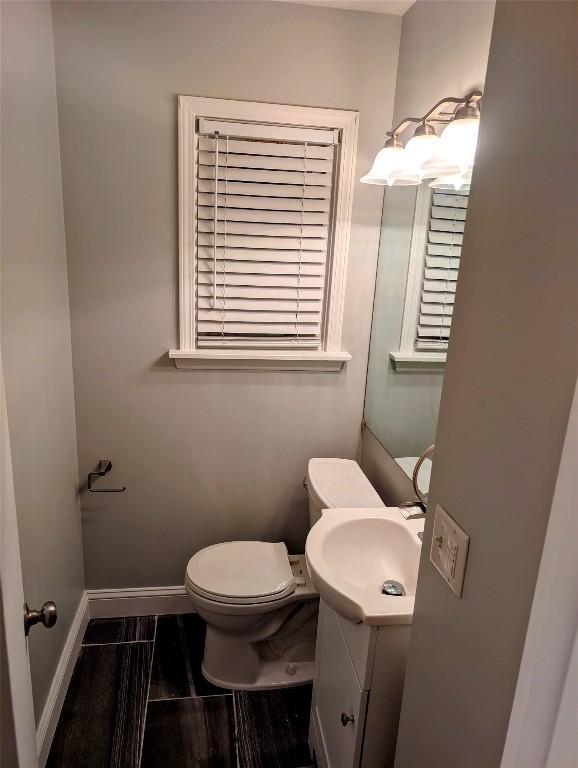 bathroom featuring wood finished floors, vanity, toilet, and baseboards