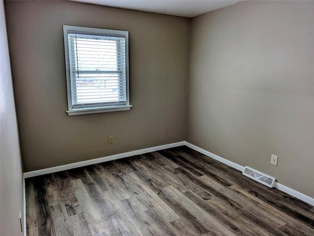 unfurnished room with dark wood finished floors, visible vents, and baseboards