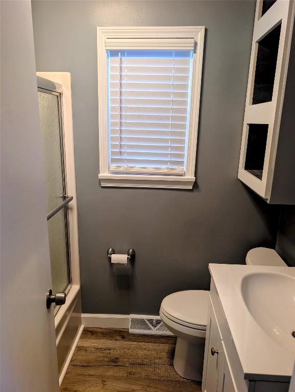 full bathroom with toilet, vanity, visible vents, baseboards, and combined bath / shower with glass door