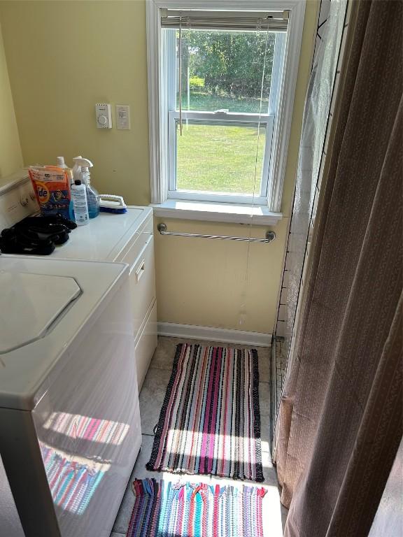 laundry area with separate washer and dryer, a wealth of natural light, and tile patterned flooring