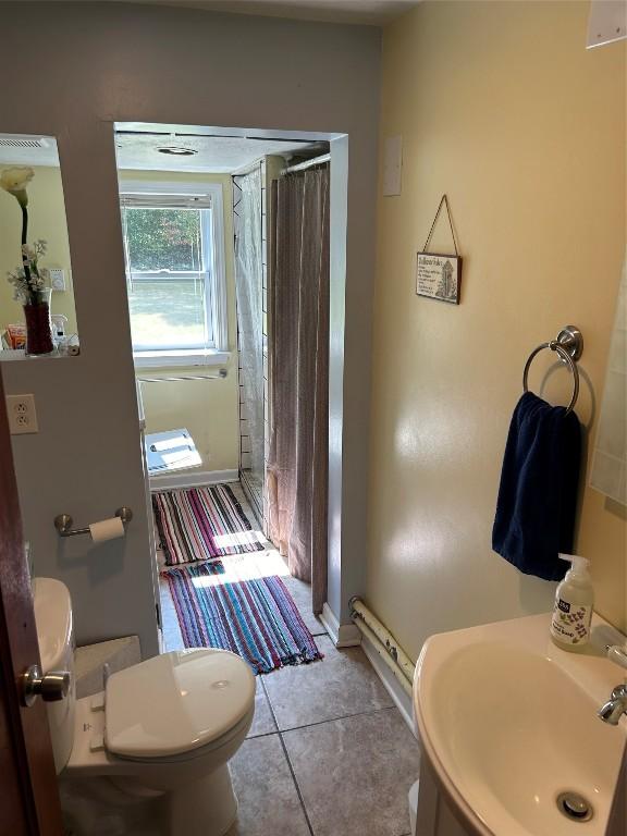 bathroom with a shower with shower curtain, tile patterned floors, toilet, and sink