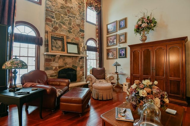 living area with a high ceiling, a fireplace, a wealth of natural light, and dark hardwood / wood-style floors