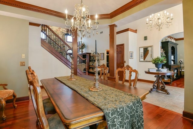 dining area featuring crown molding, wood-type flooring, and ornate columns