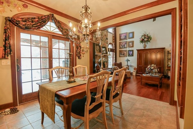 dining space with ornamental molding, a stone fireplace, an inviting chandelier, and light tile patterned floors