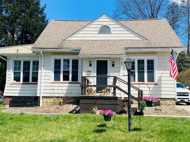 bungalow-style home with a shingled roof and a front yard