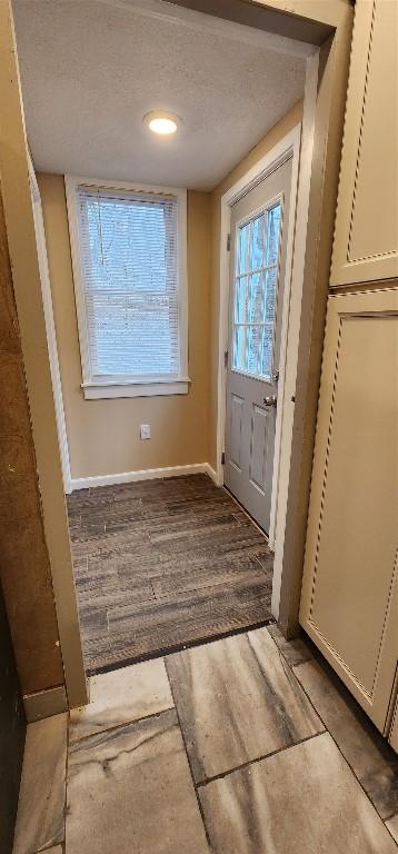 doorway to outside with a textured ceiling