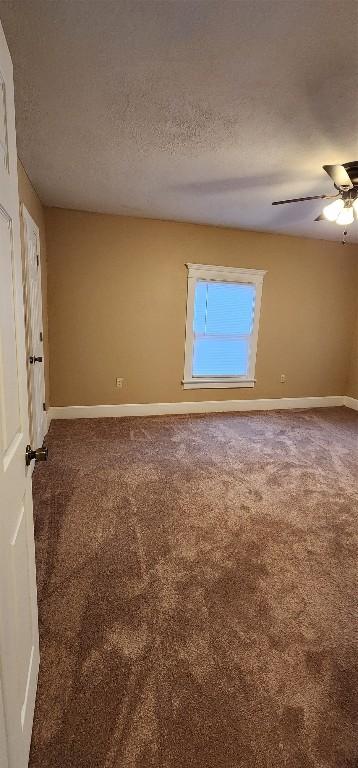 carpeted empty room featuring ceiling fan and a textured ceiling