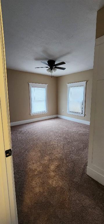 carpeted spare room featuring ceiling fan and a textured ceiling