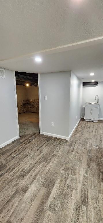 basement featuring a textured ceiling and hardwood / wood-style floors