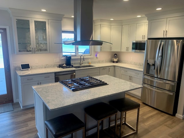 11148 Aldina Dr, Conneaut Lake, PA 16316 - kitchen featuring wood finished floors, a breakfast bar area, island range hood, stainless steel appliances, and a sink