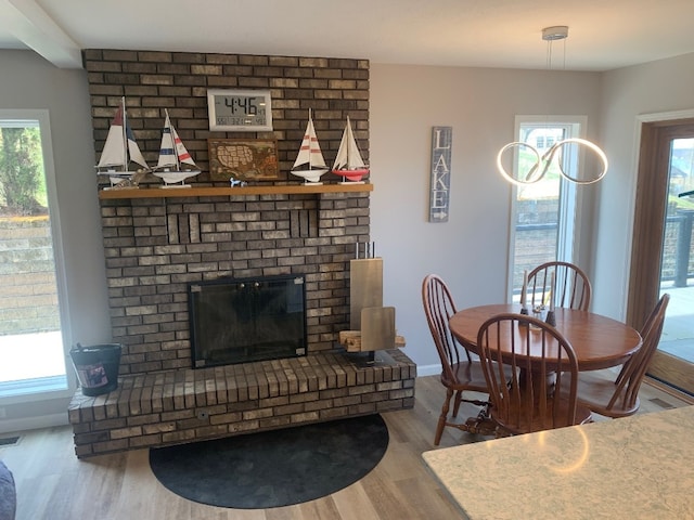 11148 Aldina Dr, Conneaut Lake, PA 16316 - dining room with visible vents, a brick fireplace, baseboards, and wood finished floors