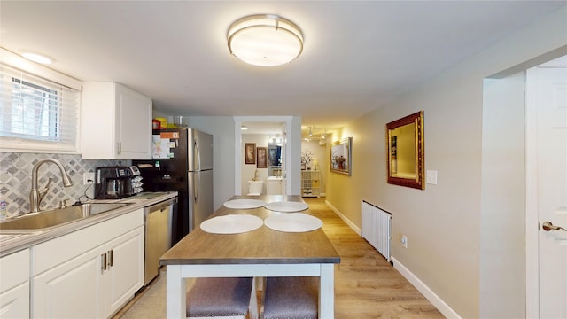 1450 Nicholson St, Erie, PA 16509 - kitchen featuring appliances with stainless steel finishes, white cabinets, tasteful backsplash, light wood-style flooring, and radiator