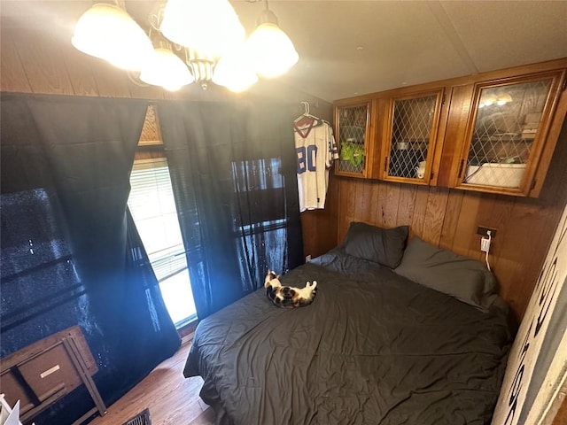 bedroom with dark hardwood / wood-style flooring, a notable chandelier, and wooden walls