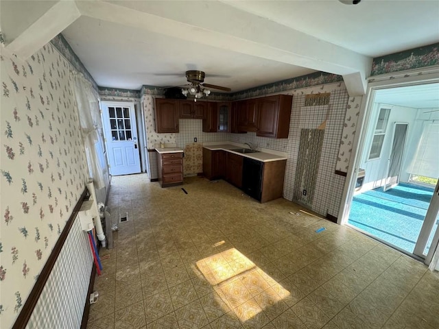 kitchen with ceiling fan, light countertops, a sink, and wallpapered walls