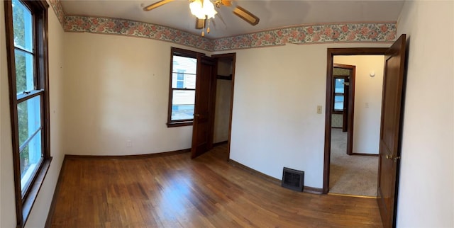 unfurnished room with visible vents, ceiling fan, baseboards, and wood finished floors