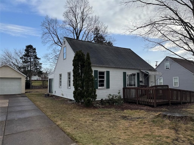 view of front of house with an outbuilding, a shingled roof, a deck, a garage, and a front lawn