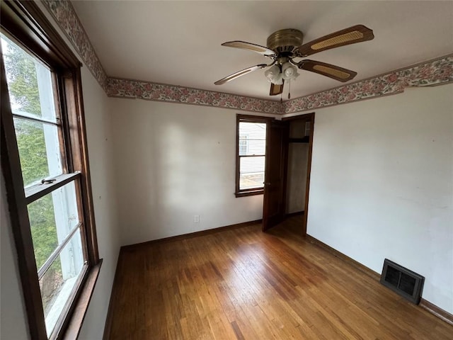 unfurnished room featuring baseboards, visible vents, ceiling fan, and hardwood / wood-style floors