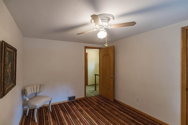 interior space featuring dark colored carpet and ceiling fan