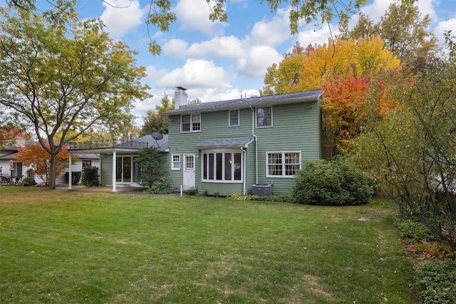 rear view of house with central air condition unit and a yard