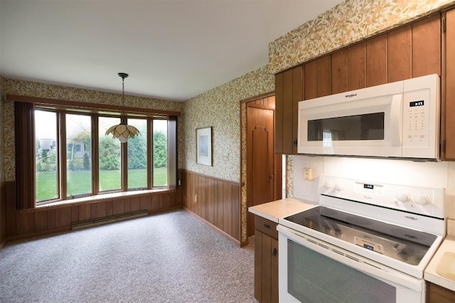 kitchen featuring light colored carpet, wood walls, white appliances, hanging light fixtures, and baseboard heating