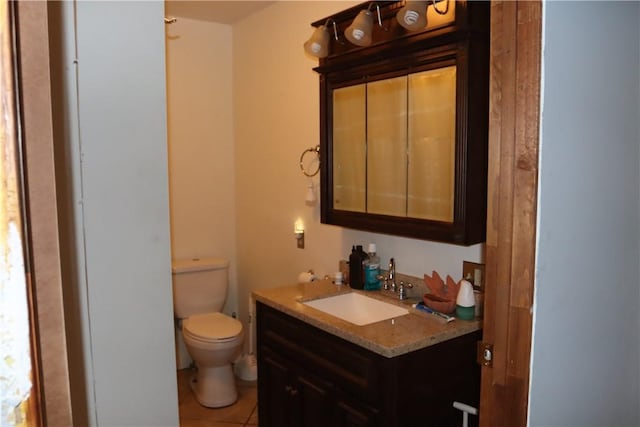 bathroom with toilet, vanity, and tile patterned floors