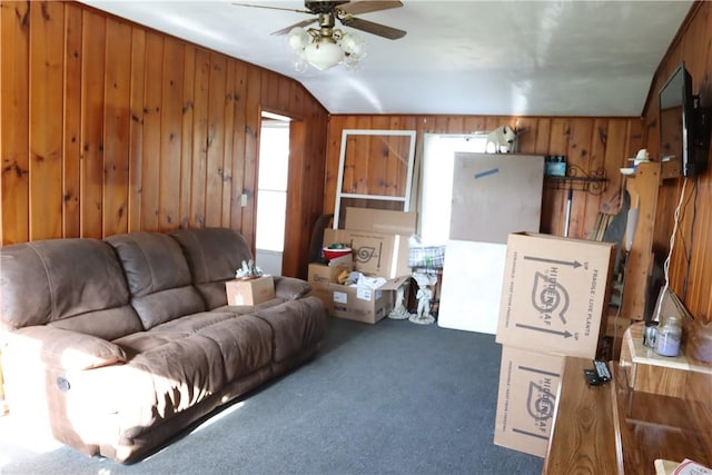 living room featuring dark colored carpet, vaulted ceiling, ceiling fan, and wood walls