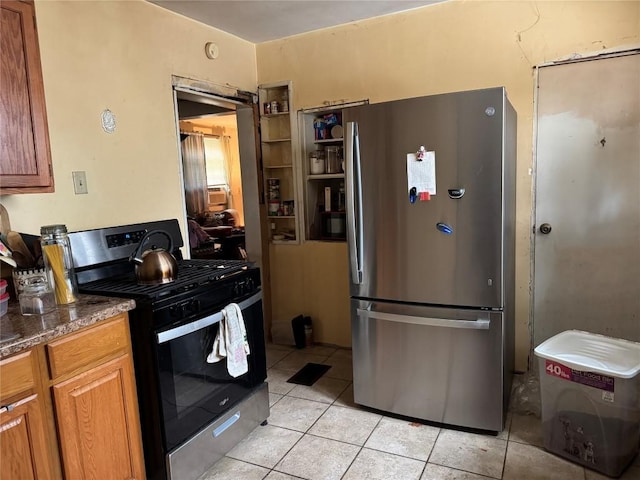 kitchen featuring stainless steel appliances, dark stone countertops, and light tile patterned floors