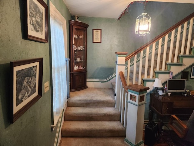 staircase featuring carpet floors and an inviting chandelier