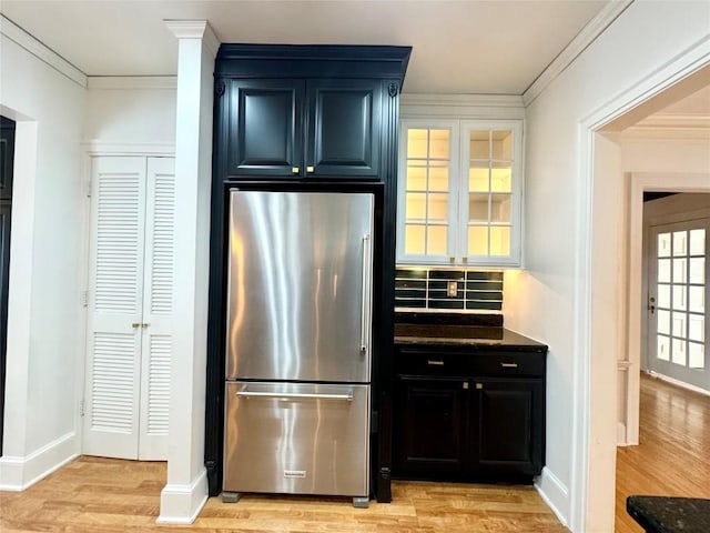 kitchen with backsplash, light hardwood / wood-style floors, stainless steel refrigerator, and ornamental molding