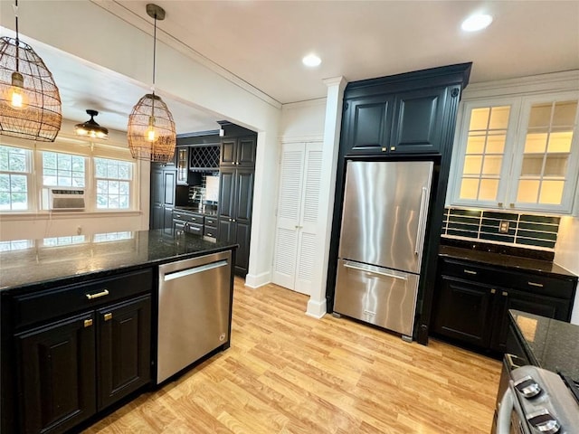 kitchen with pendant lighting, dark stone counters, decorative backsplash, appliances with stainless steel finishes, and light hardwood / wood-style floors