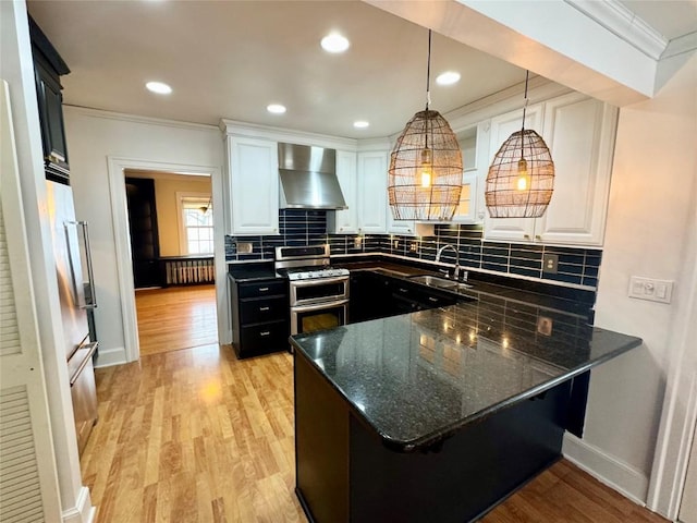 kitchen with radiator, wall chimney exhaust hood, decorative light fixtures, double oven range, and white cabinets